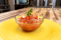 Czech Tomato Salad with Onion Glass bowl of Czech Tomato Salad with Onion, diced tomato and onion topped with parsley, on a yellow plate