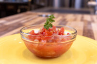Czech Tomato Salad with Onion Czech Tomato Salad with Onion in a glass bowl, garnished with parsley, on a yellow plate.