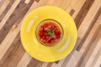 Czech Tomato Salad with Onion Glass bowl of Czech Tomato Salad with Onion, diced tomatoes and herb garnish, on a yellow plate.