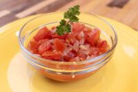 Czech Tomato Salad with Onion Glass bowl of Czech Tomato Salad with Onion, garnished with parsley, on a yellow plate