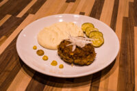 Karbenátky (Czech Burger) Karbenátky (Czech Burger) patty on a plate with mashed potatoes, pickle slices, and mustard dots.