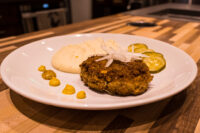 Karbenátky (Czech Burger) Karbenátky (Czech Burger) patty on a white plate with mashed potato, pickles, and mustard.