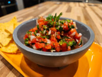 Grey bowl of Salsa with diced tomato, onion, jalapeño and cilantro, tortilla chips on the side
