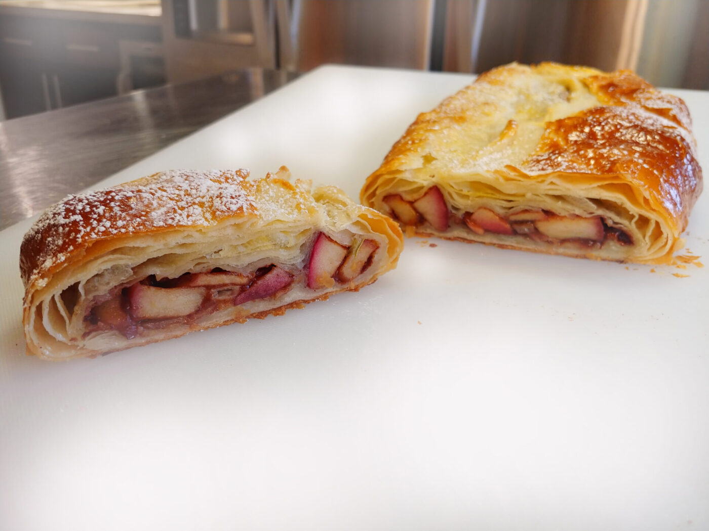 Apple Strudel Apple Strudel cut in half, showing fruit filling inside golden puff pastry, dusted with powdered sugar.