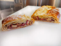 Apple Strudel Apple Strudel cut in half, showing fruit filling inside golden puff pastry, dusted with powdered sugar.