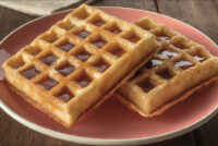 Waffles Two square Waffles drizzled with syrup, stacked on a pink plate.