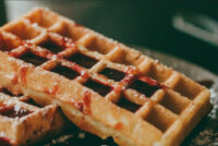 Waffles Close-up of golden Waffles with deep grid pockets, drizzled with red fruit sauce.