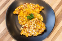 Almond Chicken Schnitzel Two almond-crusted Almond Chicken Schnitzel cutlets on a black plate with a parsley garnish.
