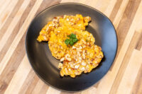 Almond Chicken Schnitzel Almond Chicken Schnitzel pieces on a black plate, coated in sliced almonds and garnished with parsley.