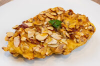 Almond Chicken Schnitzel with a golden almond crust, garnished with parsley, on a white plate.