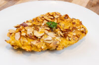 Almond Chicken Schnitzel Almond Chicken Schnitzel with a crispy sliced-almond crust and parsley garnish on a white plate