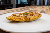 Almond Chicken Schnitzel Golden Almond Chicken Schnitzel with a crisp sliced almond crust on a white plate.