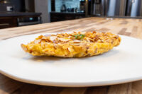 Almond Chicken Schnitzel Golden Almond Chicken Schnitzel topped with sliced almonds and herb garnish on a white plate