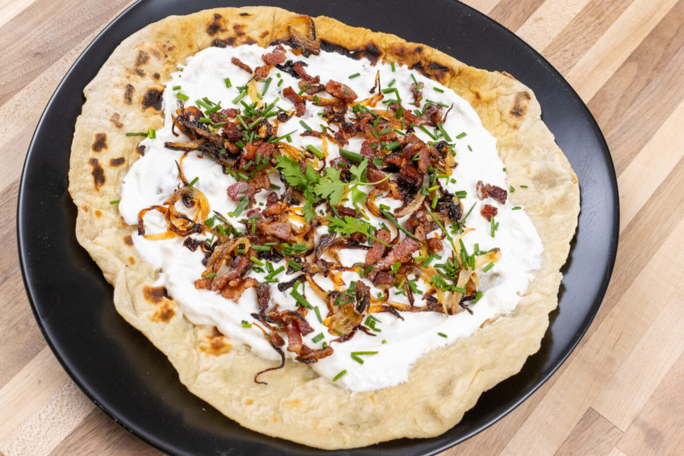 Lokše Flat Bread with Bryndza Cheese Substitute and Bacon Lokše Flat Bread with Bryndza Cheese Substitute and Bacon, topped with white cheese sauce, bacon, and herbs