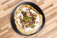 Lokše Flat Bread with Bryndza Cheese Substitute and Bacon Lokše Flat Bread with Bryndza Cheese Substitute and Bacon topped with white sauce, crispy onions, bacon bits, and chives.