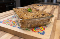Baked Mushroom Kuba (Houbovy Kuba) in a glass dish, topped with a herb sprig, on a painted board