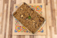 Glass dish of Mushroom Kuba (Houbovy Kuba) with barley and mushroom slices, garnished with herb, on a floral board.