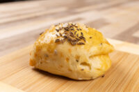 Golden baked Pagáče (Pagache) bun with caraway seeds and coarse salt on a wooden board.
