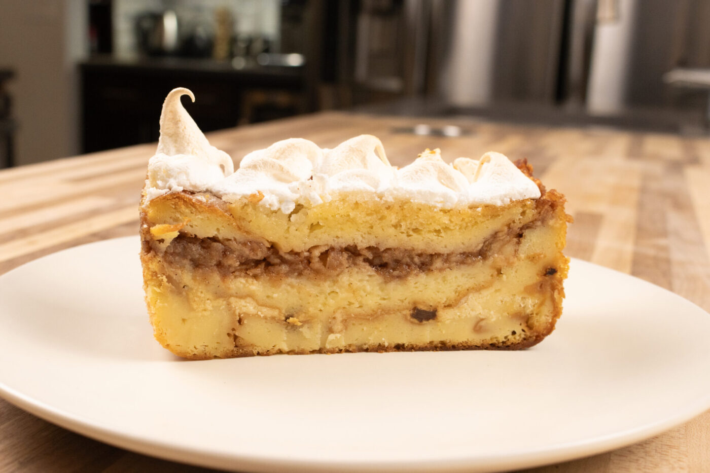 Cross-section slice of Žemlovka – Apple Bread Pudding showing bread and apple layers under toasted meringue.