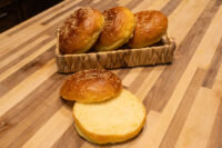Burger Buns Four sesame-topped Burger Buns in a woven basket, one sliced open on a wooden counter