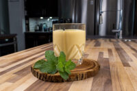 Czech Egg Liqueur – Czech Eggnog Glass of Czech Egg Liqueur – Czech Eggnog, pale yellow and creamy, on a wood slice with mint.