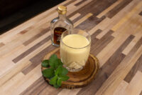 Czech Egg Liqueur – Czech Eggnog Glass of Czech Egg Liqueur – Czech Eggnog garnished with mint, small bottle behind it on wooden counter.