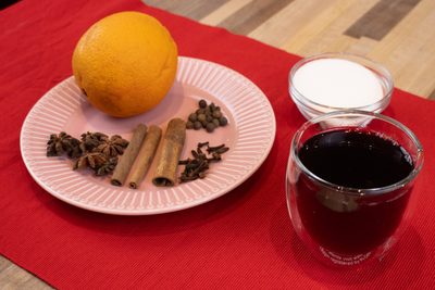 Czech Mulled Wine Svarak Orange, cinnamon, star anise and cloves on a plate with sugar and a glass of Czech Mulled Wine Svarak.