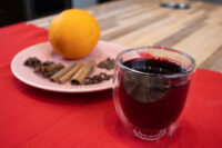Czech Mulled Wine Svarak Glass of Czech Mulled Wine Svarak beside a pink plate with orange, cinnamon sticks, and cloves.