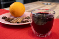 Czech Mulled Wine Svarak Glass of Czech Mulled Wine Svarak beside a plate of cloves, cinnamon sticks, and an orange.