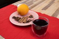 Czech Mulled Wine Svarak Glass of Czech Mulled Wine Svarak beside a pink plate with an orange, cinnamon sticks, and cloves.