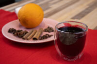 Czech Mulled Wine Svarak Glass of Czech Mulled Wine Svarak beside an orange, cinnamon, star anise and cloves on a red cloth