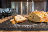 Sliced Christmas Vánočka (Houska) loaf with raisins and almond topping, dusted with powdered sugar