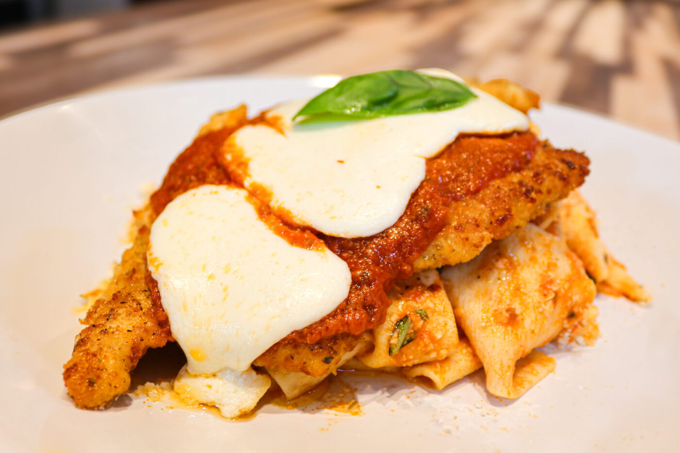 Chicken Parmesan Breaded Chicken Parmesan topped with marinara, melted mozzarella, and basil, plated over pasta