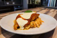 Chicken Parmesan Chicken Parmesan with melted mozzarella and marinara sauce over rigatoni, garnished with basil.