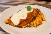 Chicken Parmesan Breaded Chicken Parmesan topped with marinara sauce, melted cheese, and basil, plated over ribbon pasta.