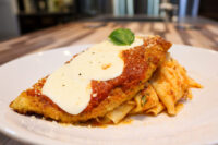 Chicken Parmesan Chicken Parmesan cutlet with marinara and melted mozzarella, basil garnish, served with red-sauced pasta