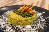 Asparagus Risotto with Shrimp Plated Asparagus Risotto with Shrimp topped with grilled asparagus spears, dusted with parmesan on a black plate.