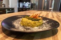 Asparagus Risotto with Shrimp Black plate of Asparagus Risotto with Shrimp topped with asparagus tips and curled fried shrimp, dusted with parmesan.