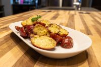 Baby Red Potatoes with Butter Halved red and yellow baby potatoes with butter, pepper, and herb garnish on a white oval plate.