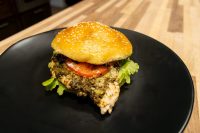 Pesto Chicken Sandwich with Parmesan Pesto Chicken Sandwich with Parmesan on a sesame bun with tomato and lettuce, served on a black plate.