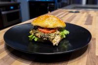 Pesto Chicken Sandwich with Parmesan Pesto Chicken Sandwich with Parmesan on a sesame bun with lettuce and tomato on a black plate