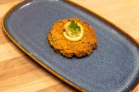 Golden fried Tuna Cake topped with a lemon slice and parsley, served on a blue ceramic plate.