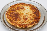 60 min. Pan Pizza A whole 60 min. Pan Pizza with bubbly browned cheese and thick crust on a metal pan.