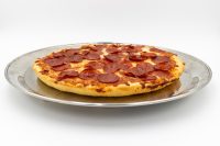 60 min. Pan Pizza 60 min. Pan Pizza with pepperoni and melted cheese on a thick golden crust, served on a metal tray.