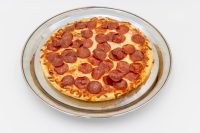 60 min. Pan Pizza Overhead view of a 60 min. Pan Pizza topped with pepperoni and melted cheese on a round metal plate.