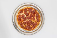 60 min. Pan Pizza Overhead view of a whole 60 min. Pan Pizza topped with pepperoni on a metal pan.
