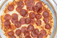 60 min. Pan Pizza Overhead view of a 60 min. Pan Pizza with melted cheese and pepperoni slices in a metal pan.