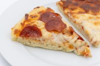 60 min. Pan Pizza A slice of 60 min. Pan Pizza with melted cheese and pepperoni on a white plate.