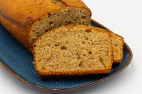 Sliced loaf of Banana Bread with golden crust and moist crumb on a dark blue plate.