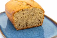 Sliced Banana Bread loaf with golden crust and tan crumb on a blue ceramic plate.